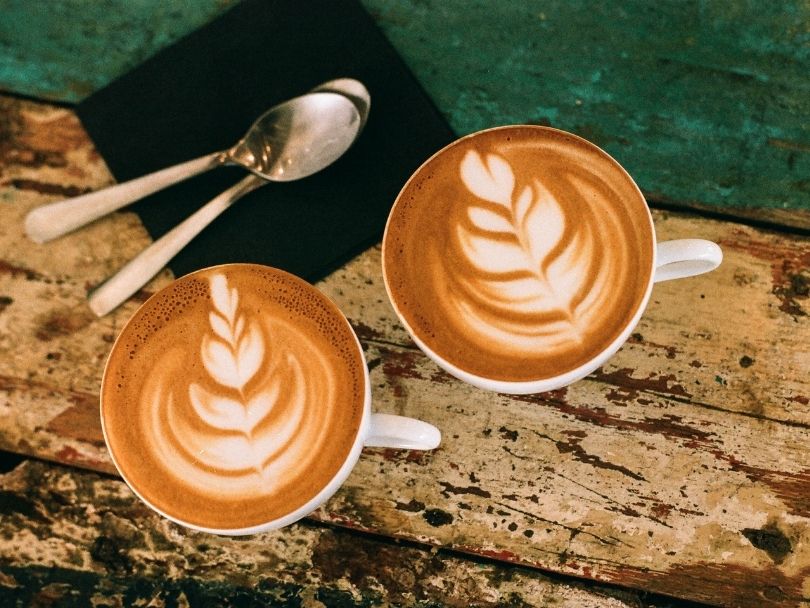 Twee identiek uitziende kopjes, één met caffe mocha en één met caffe latte.