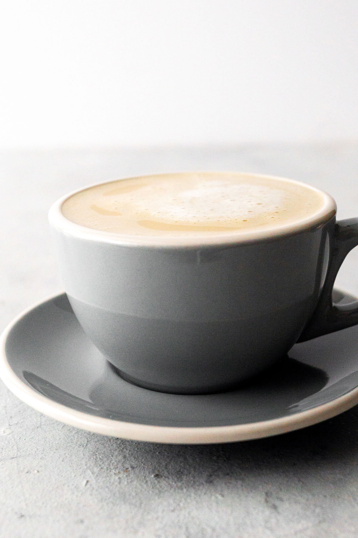 Cafe au lait in een grijze mok met schotel.