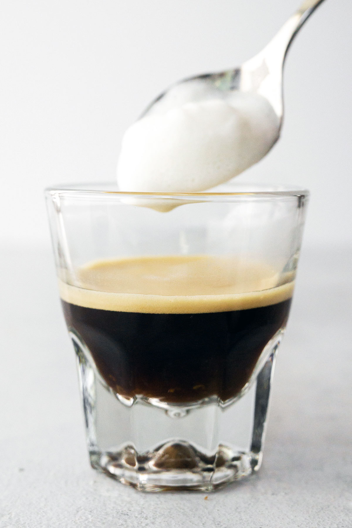 Lepel melkschuim op espresso.