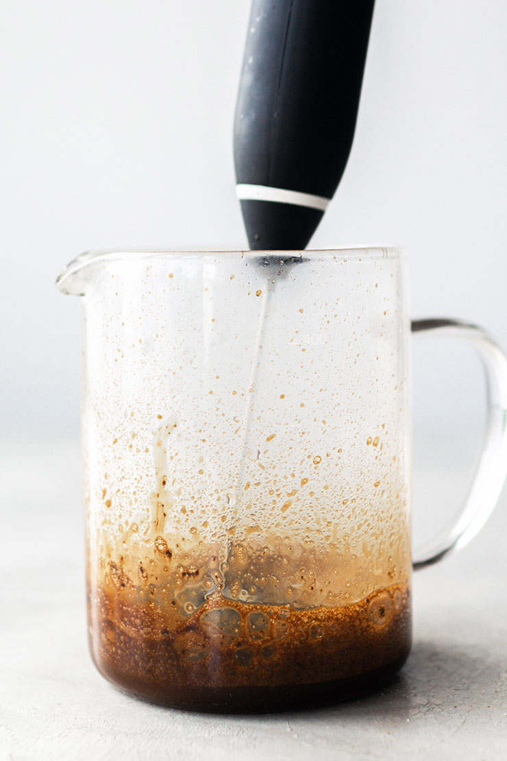 Oploskoffie, suiker en water in een glazen bak kloppen.