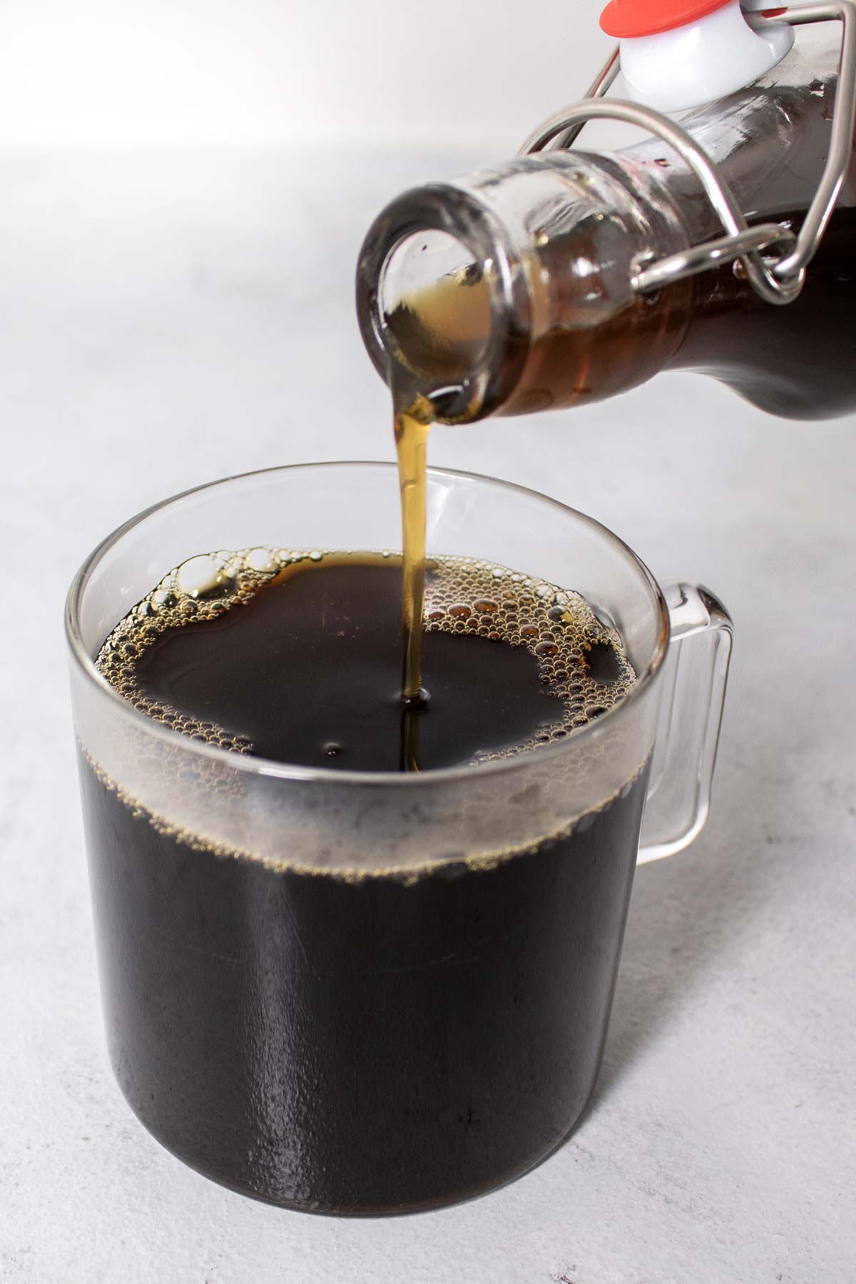 Bruine suikersiroop in een kopje koffie gieten.
