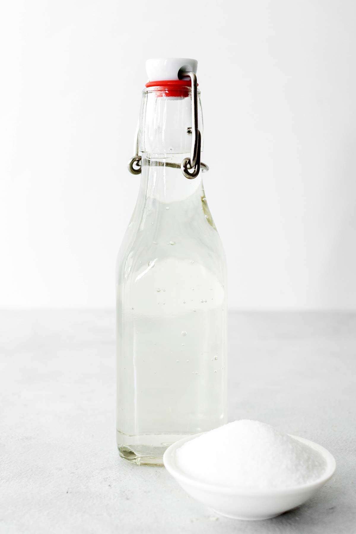 Zelfgemaakte eenvoudige siroop in een glazen fles met een kommetje kristalsuiker.