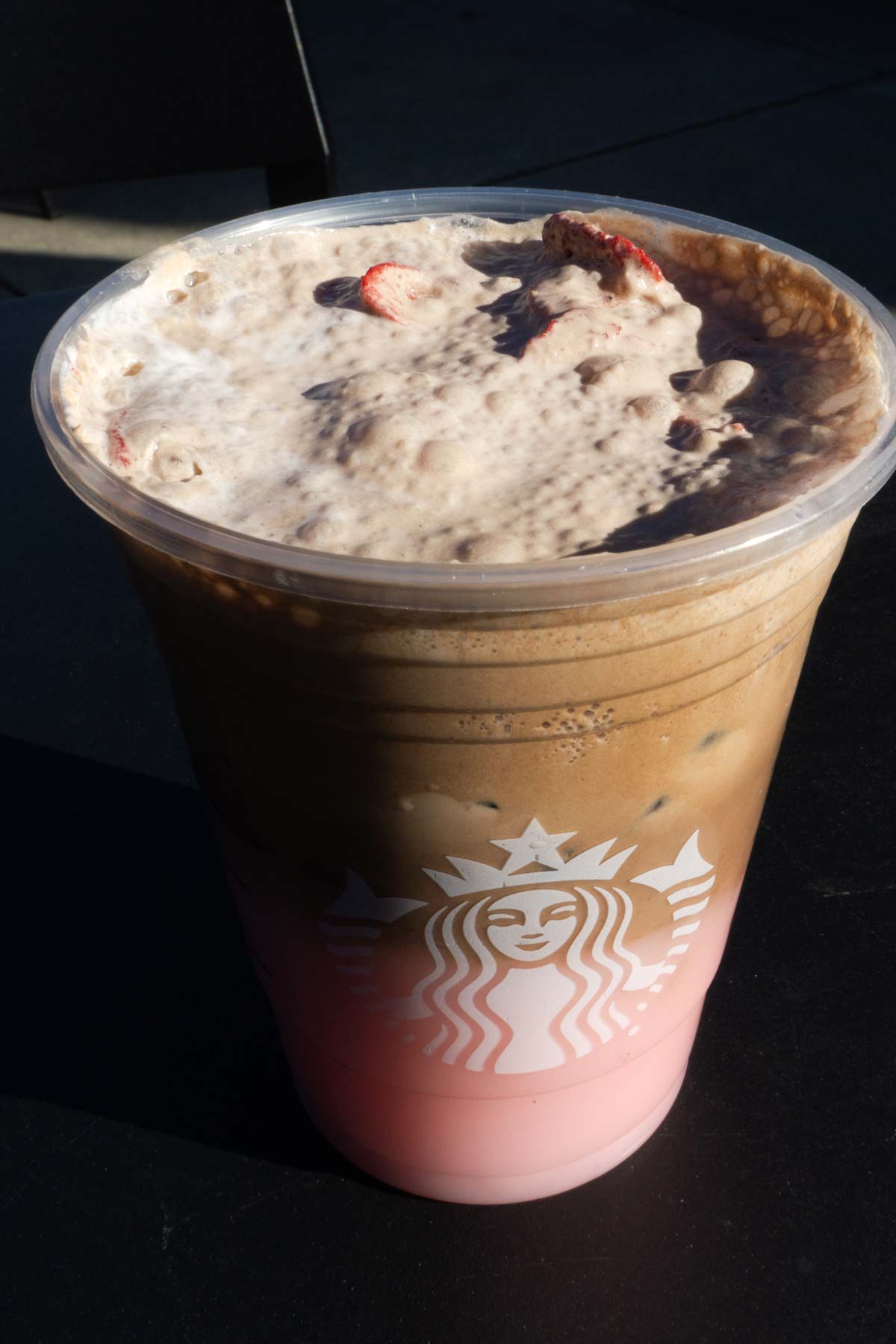 Grote beker Starbucks gelaagde Pink Drink met chocolade koudschuim in een beker met ijs bedekt met gedroogde aardbeien.