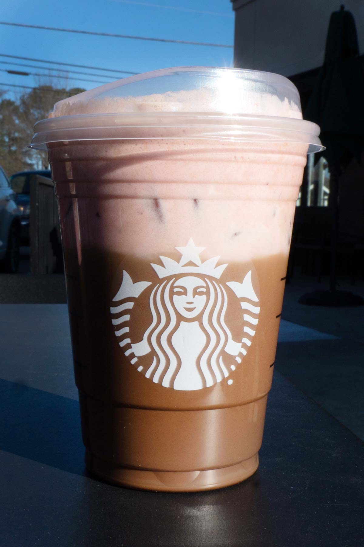 Grande sized Starbucks gelaagde mokka en aardbeiendrank in een beker met een deksel.