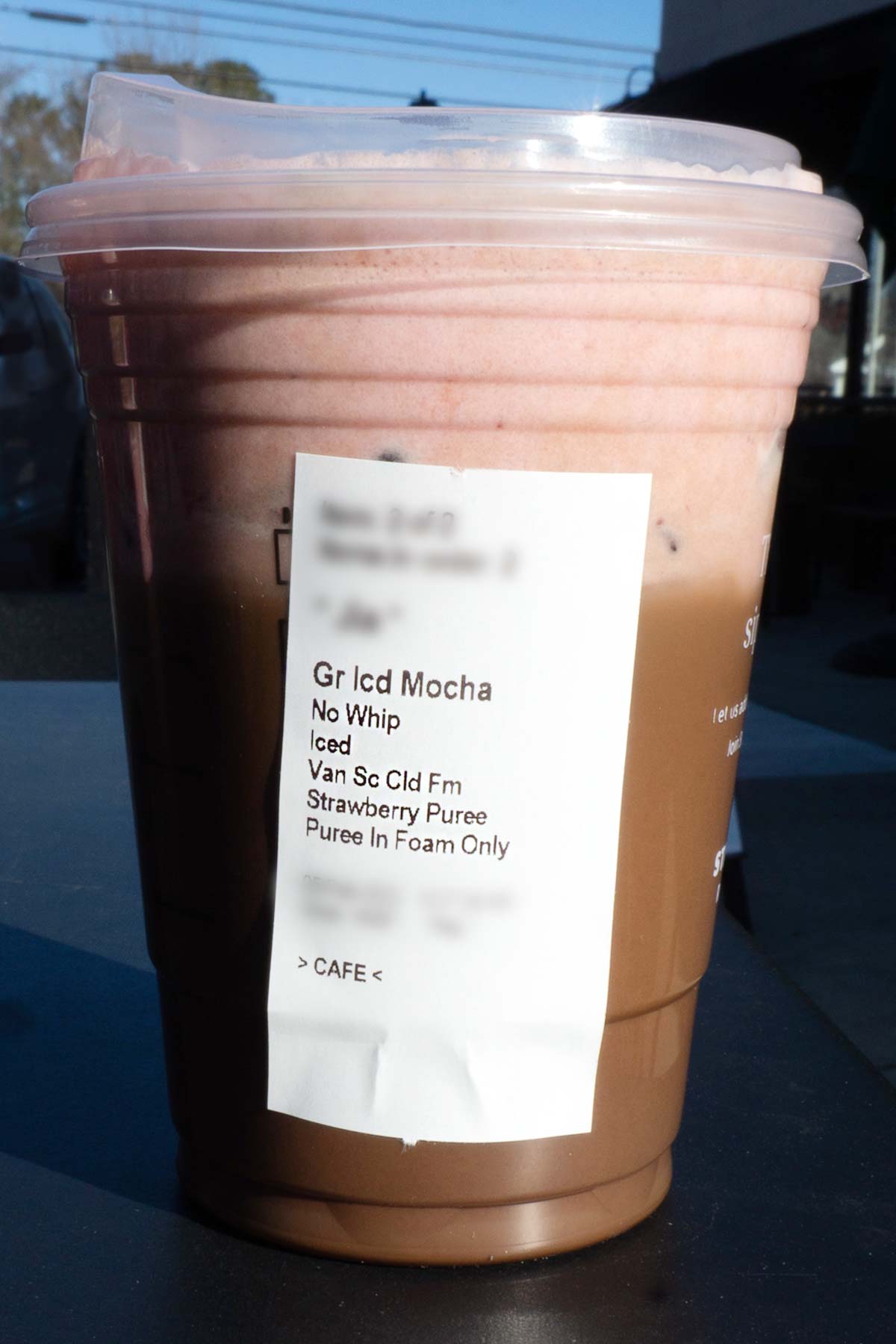 Grande sized Starbucks gelaagde mokka en aardbeiendrank in een beker met de ingrediënten vermeld op een etiket op de beker.