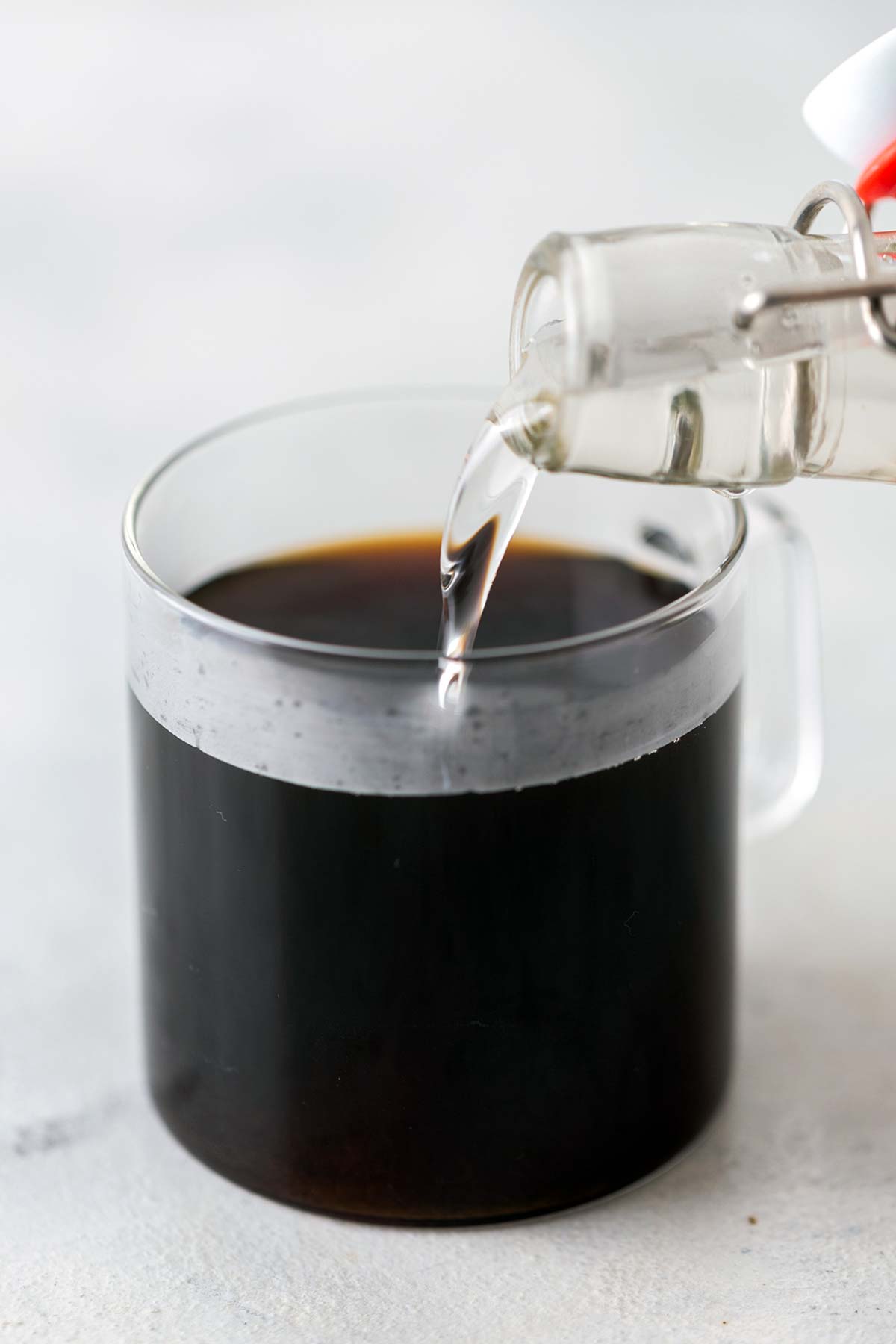 Een fles klassieke siroop die in een kopje koffie wordt gegoten.