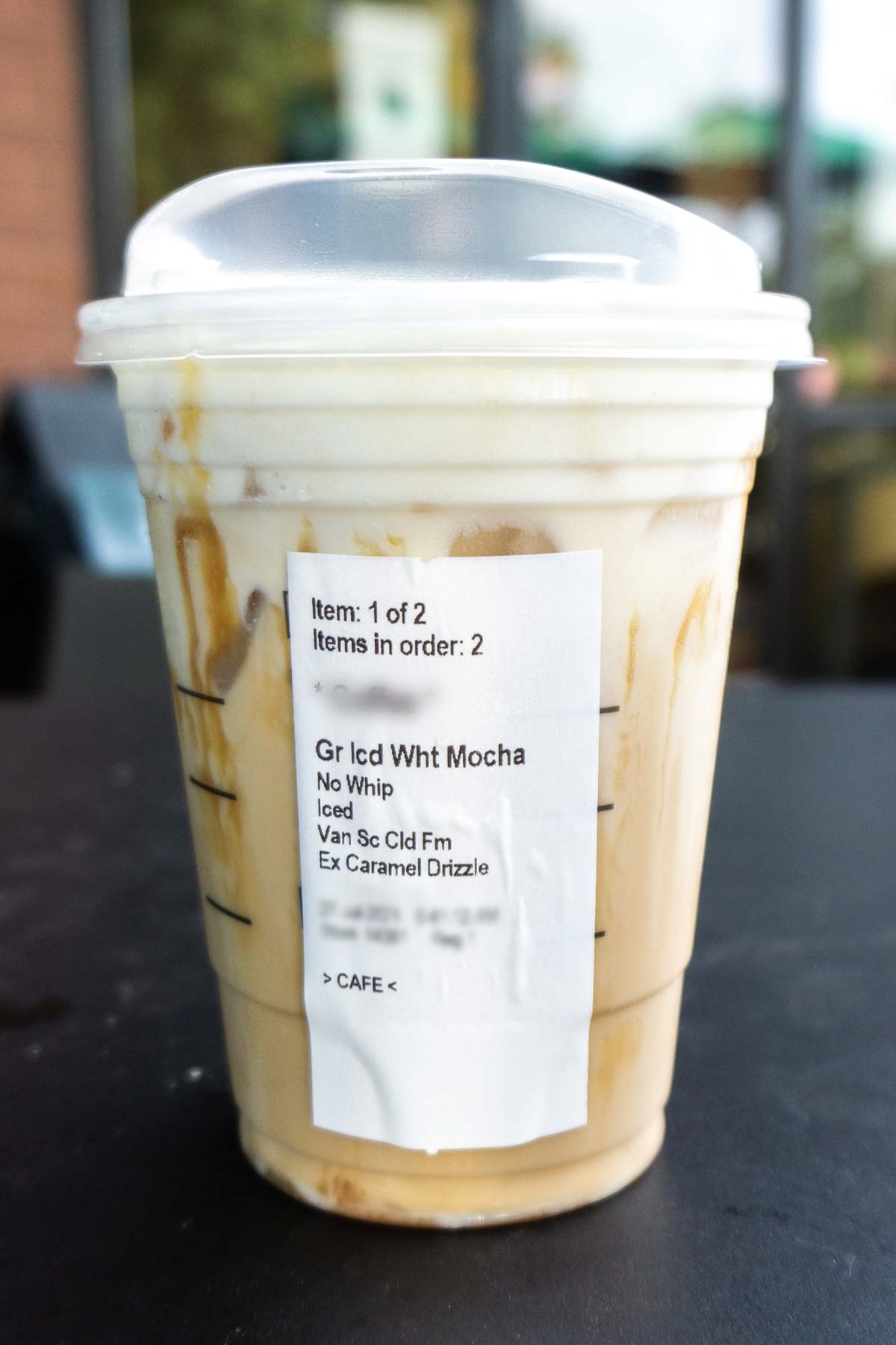 Starbucks drinkt Iced White Mocha met Sweet Cream Foam en extra karamel motregen in een plastic beker.